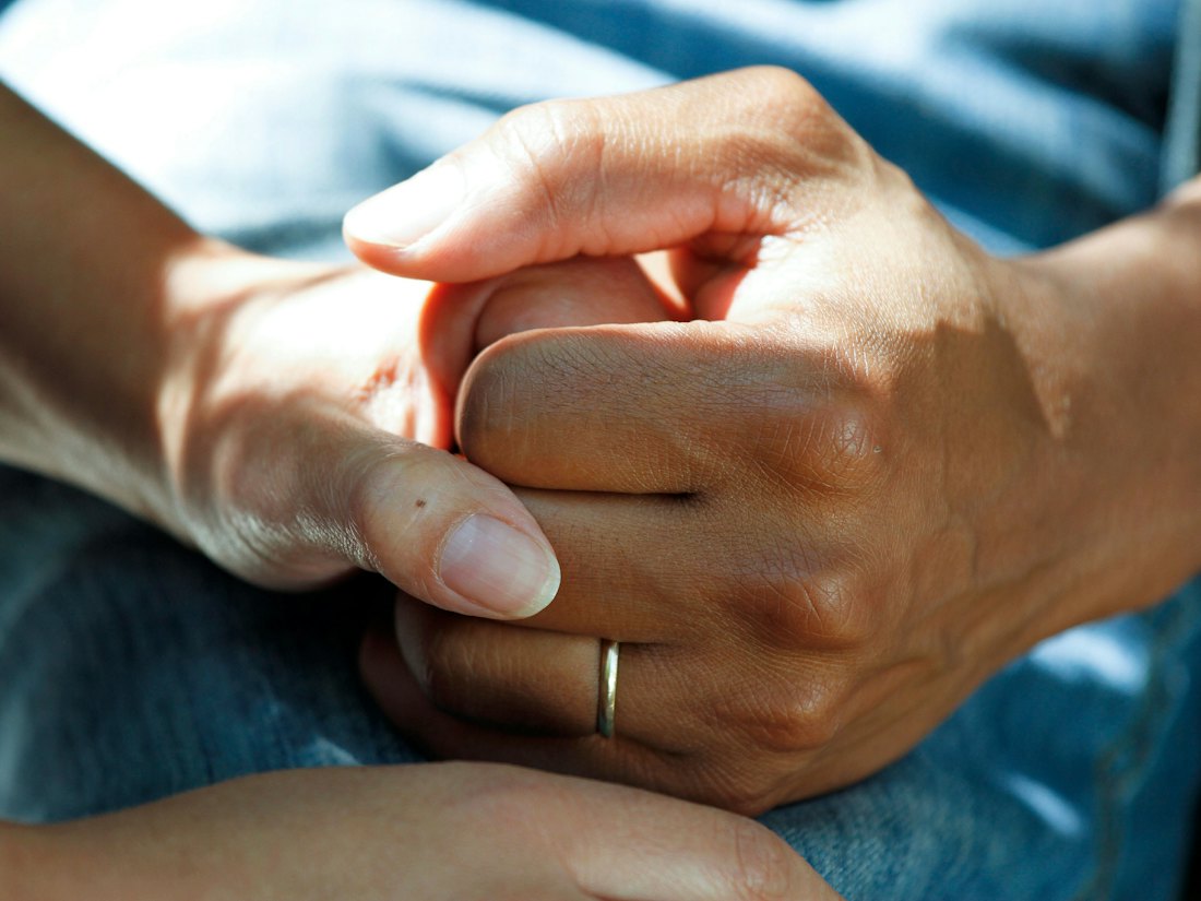 Close-up of a carer gently holding an older person's hands