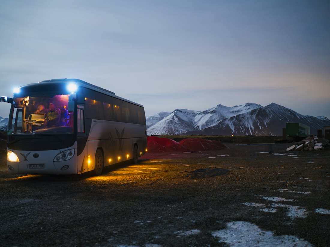 Minibus with headlights on, parked on a quiet rural road at dusk
